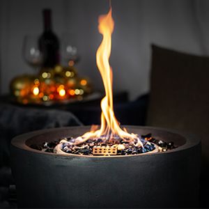 Gaskamin mit gemütlicher Flamme und Weinflasche im Hintergrund